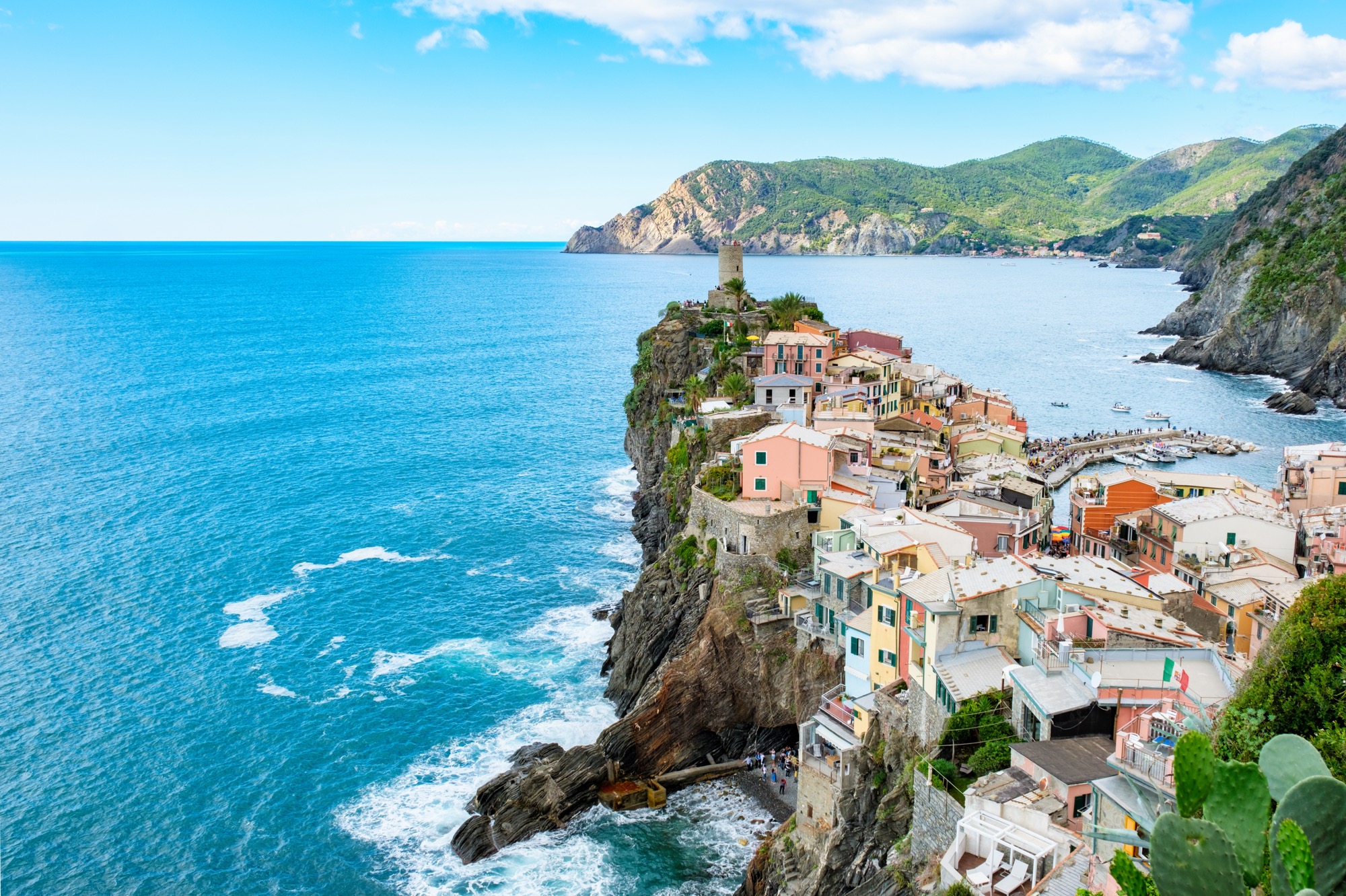 Maisons colorées typiques sur la côte italienne des Pouilles, face à la mer turquoise sous un ciel ensoleillé.